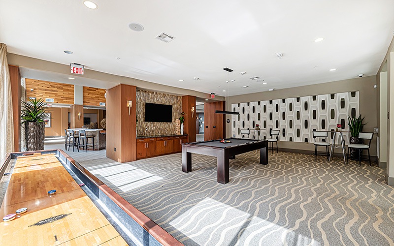 a large lounge with a shuffleboard table pool table and tv